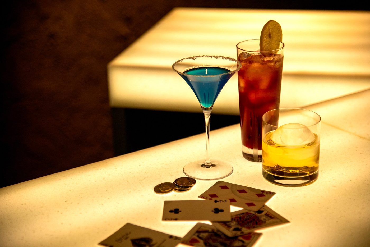 A craft cocktail beside a fanned deck of playing cards at BAR21